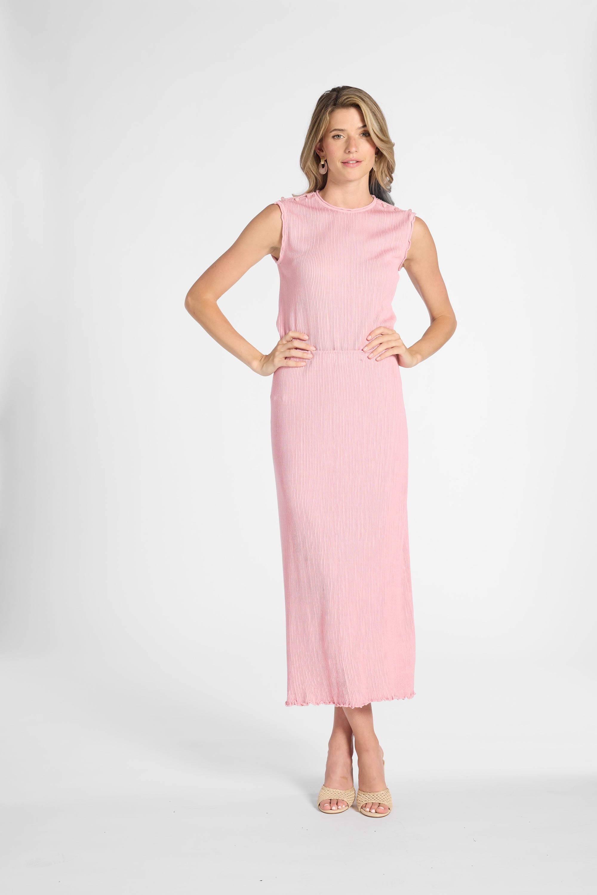 Woman modeling a pleated pink skirt with the matching shell on a white backdrop
