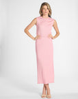 Woman modeling a pleated pink skirt with the matching shell on a white backdrop