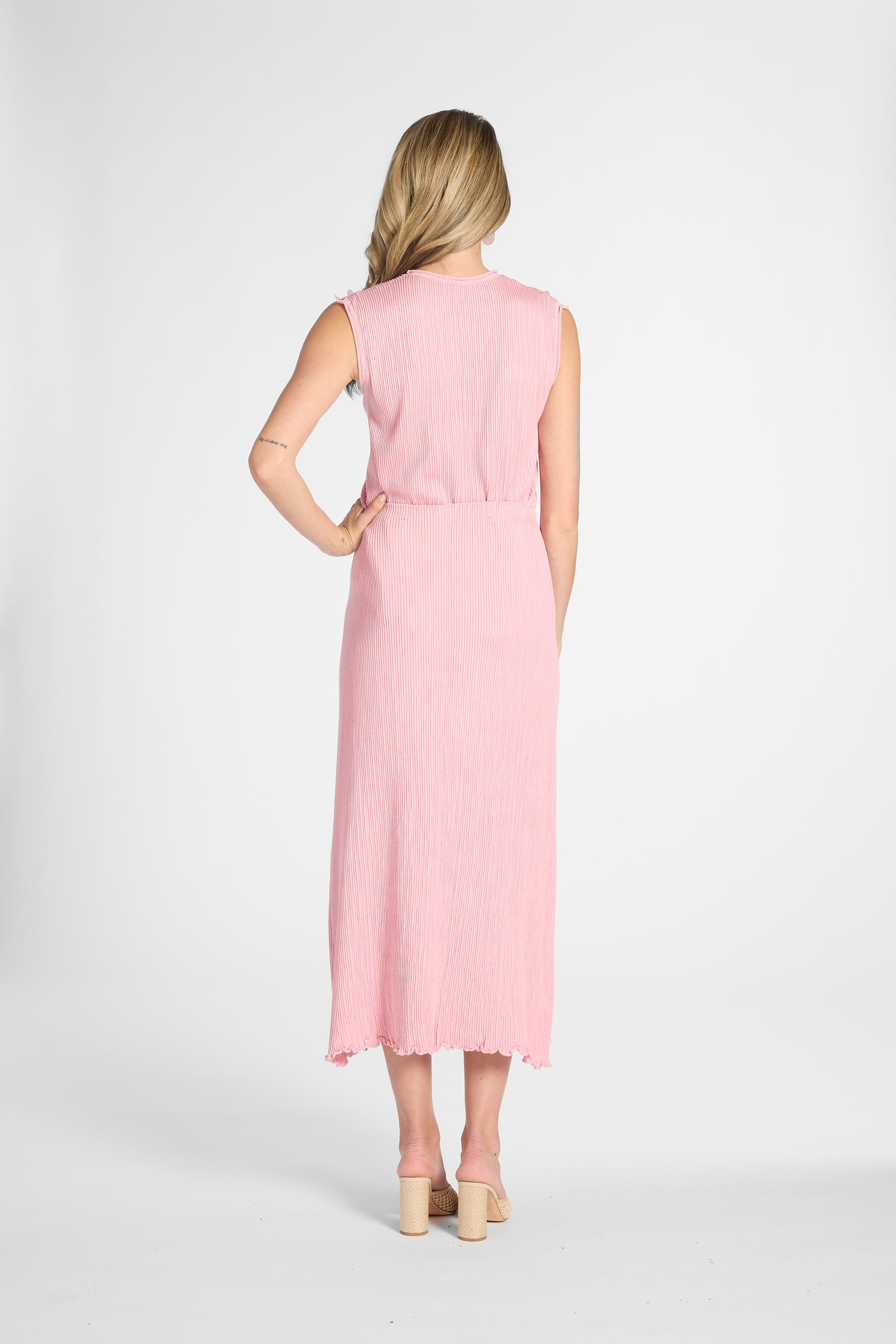 Woman modeling a light pink pleated skirt and shell on a white background