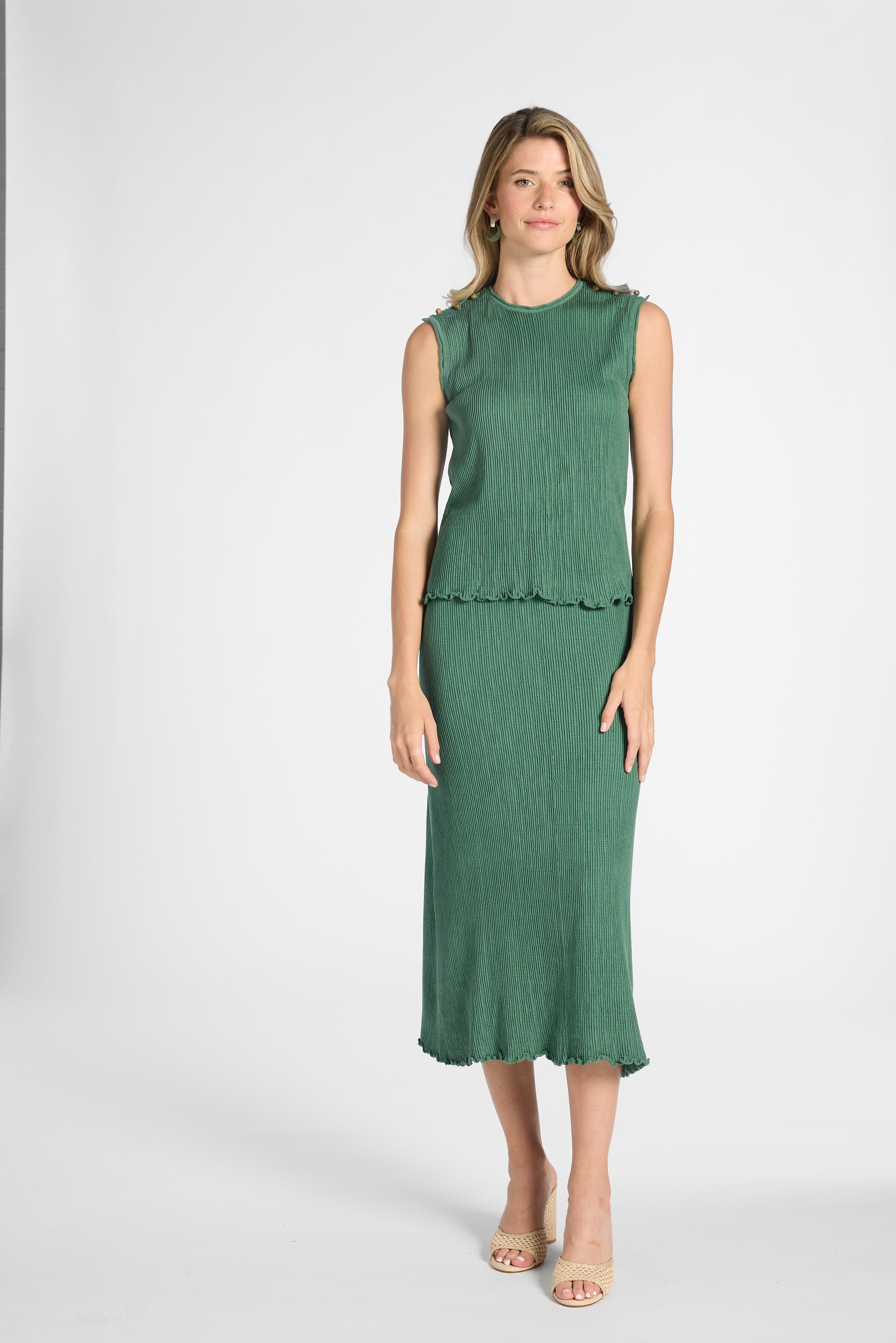 Woman modeling a sage green pleated skirt and shell on a white backdrop