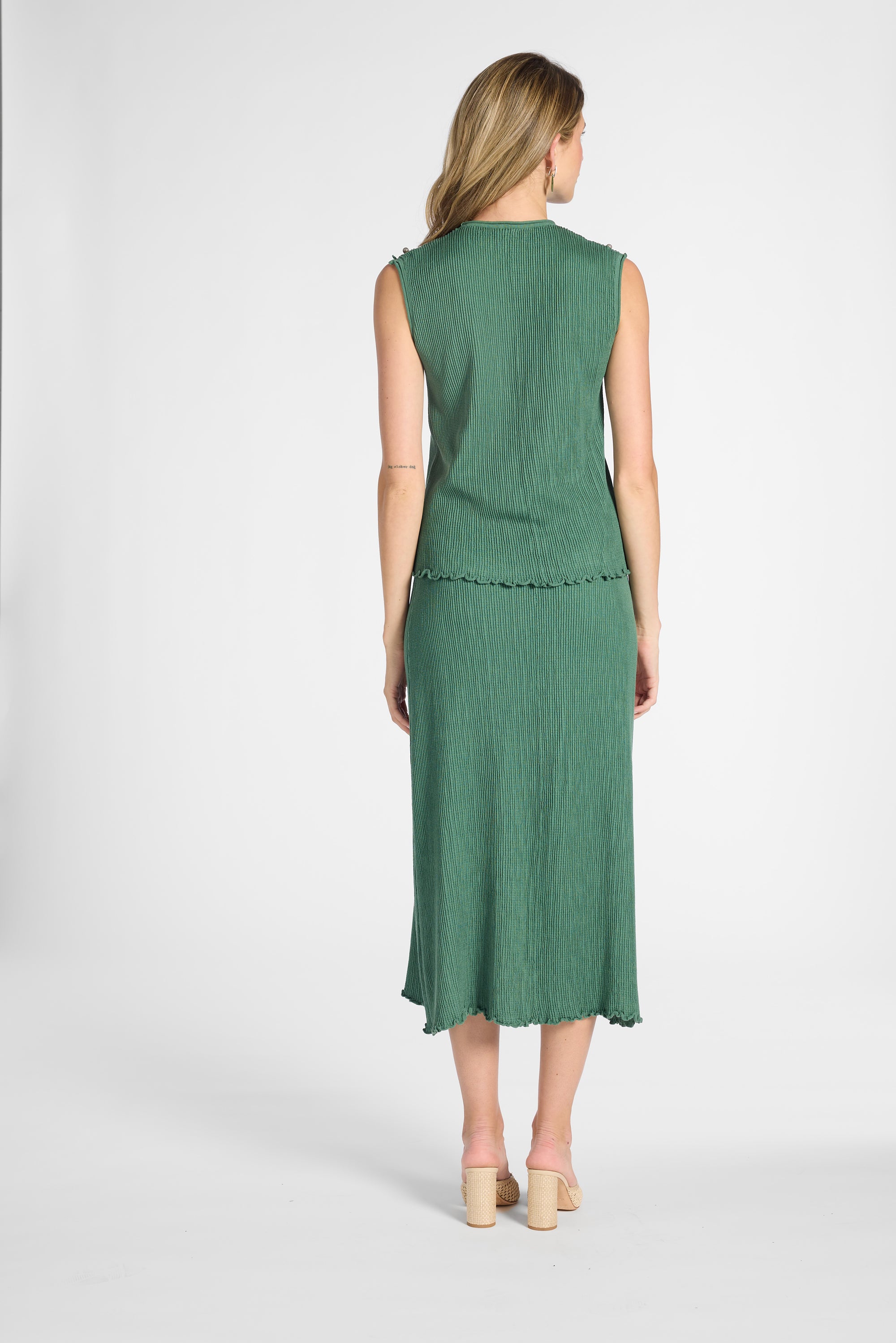 Woman standing from the bank with a pleated shell and skirt set on a white backdrop