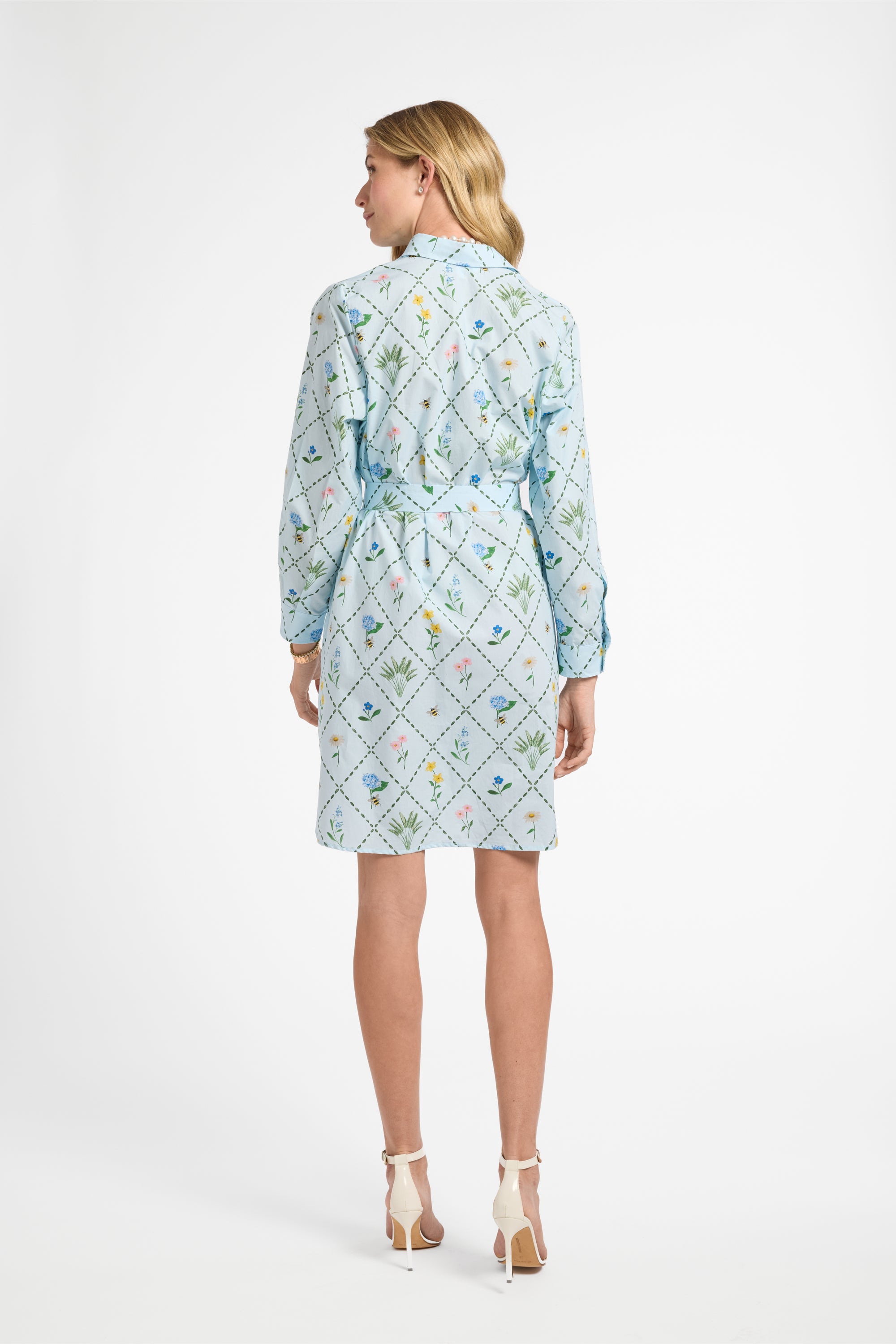 Woman wearing a light blue dress with a geometric floral pattern on a white background