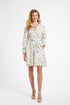 Woman modeling a mid-length white floral dress on a white backdrop