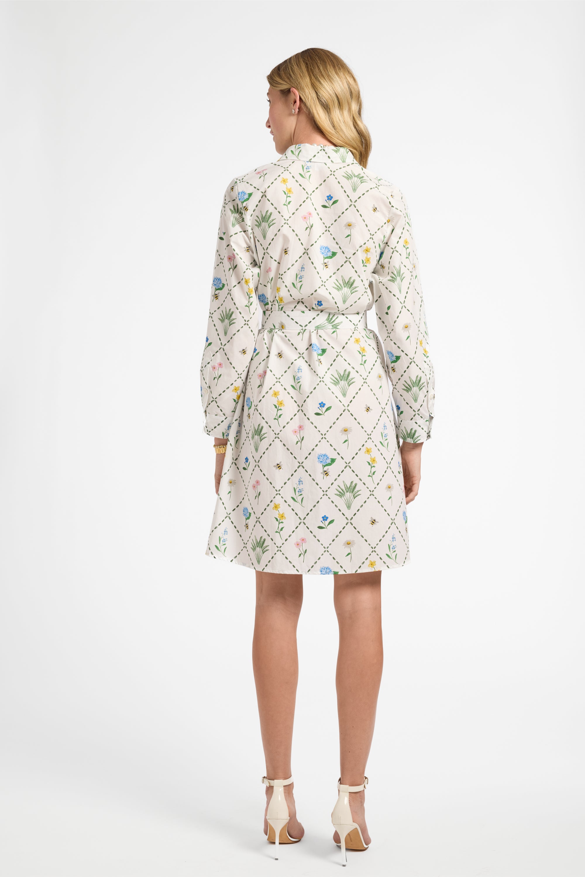 Woman facing away wearing a long sleeve white floral dress