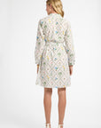 Woman facing away wearing a long sleeve white floral dress
