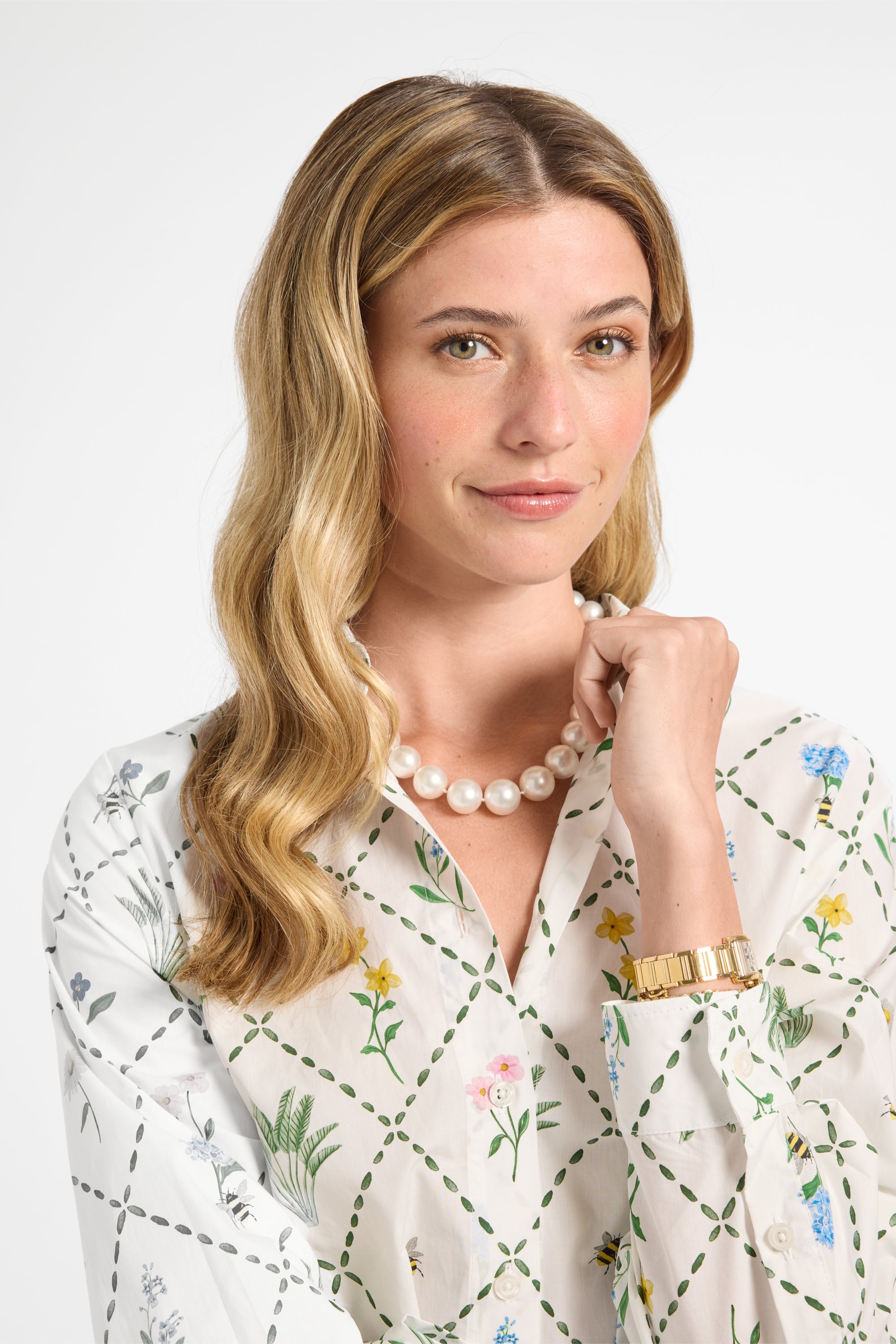 Woman modeling a white floral long sleeve dress on a white backdrop
