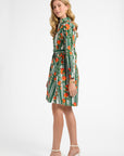 Woman wearing a green and white dress with orange patterns on a white background