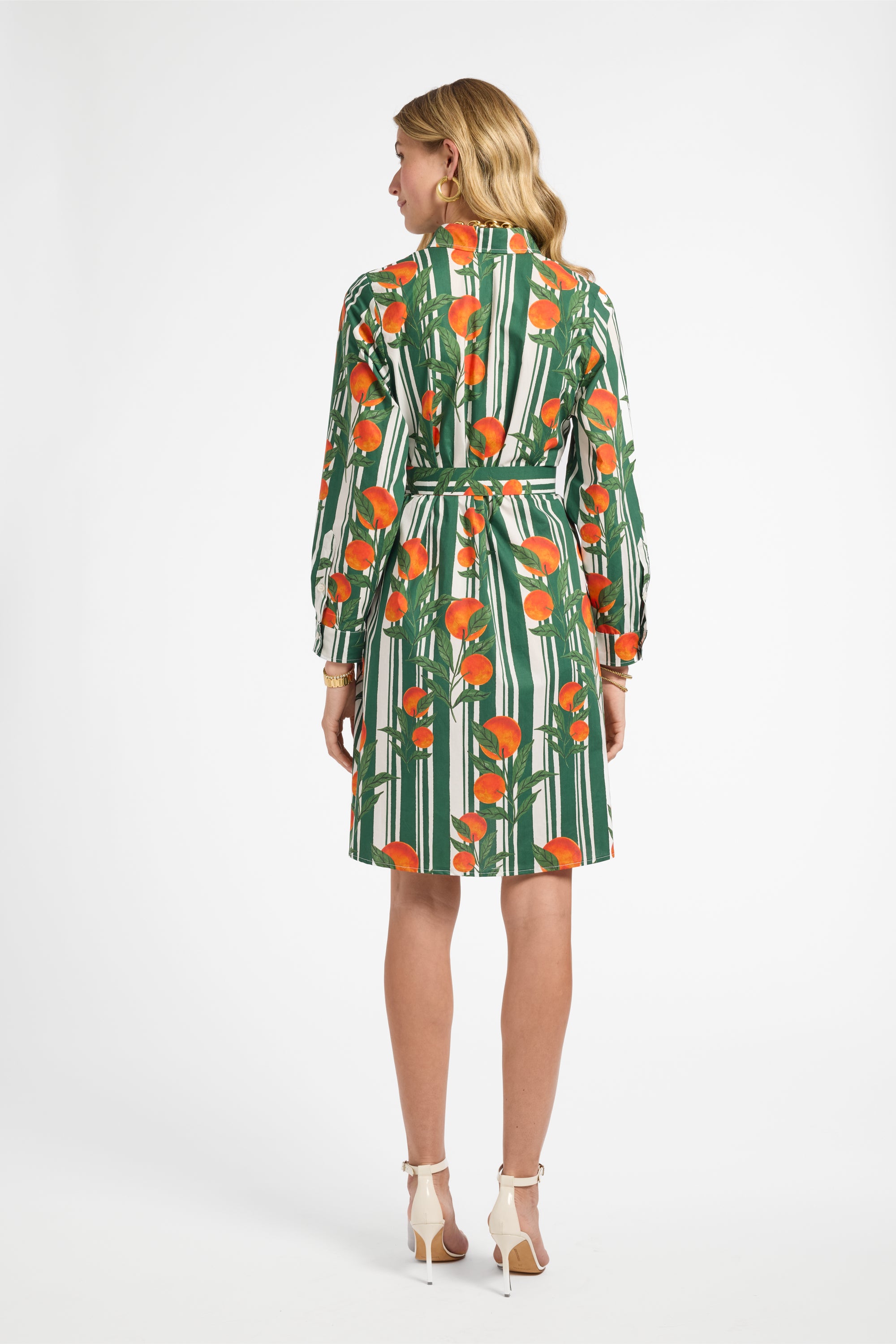 Woman wearing a green and orange patterned dress on a white background