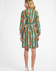 Woman wearing a green and orange patterned dress on a white background