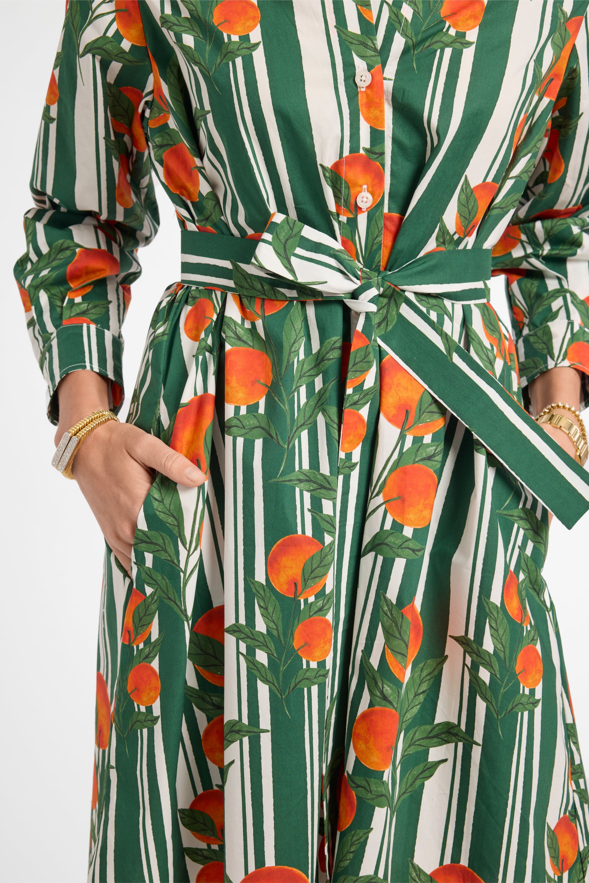 Green and white striped dress with orange fruit pattern worn by a person.