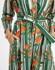 Green and white striped dress with orange fruit pattern worn by a person.