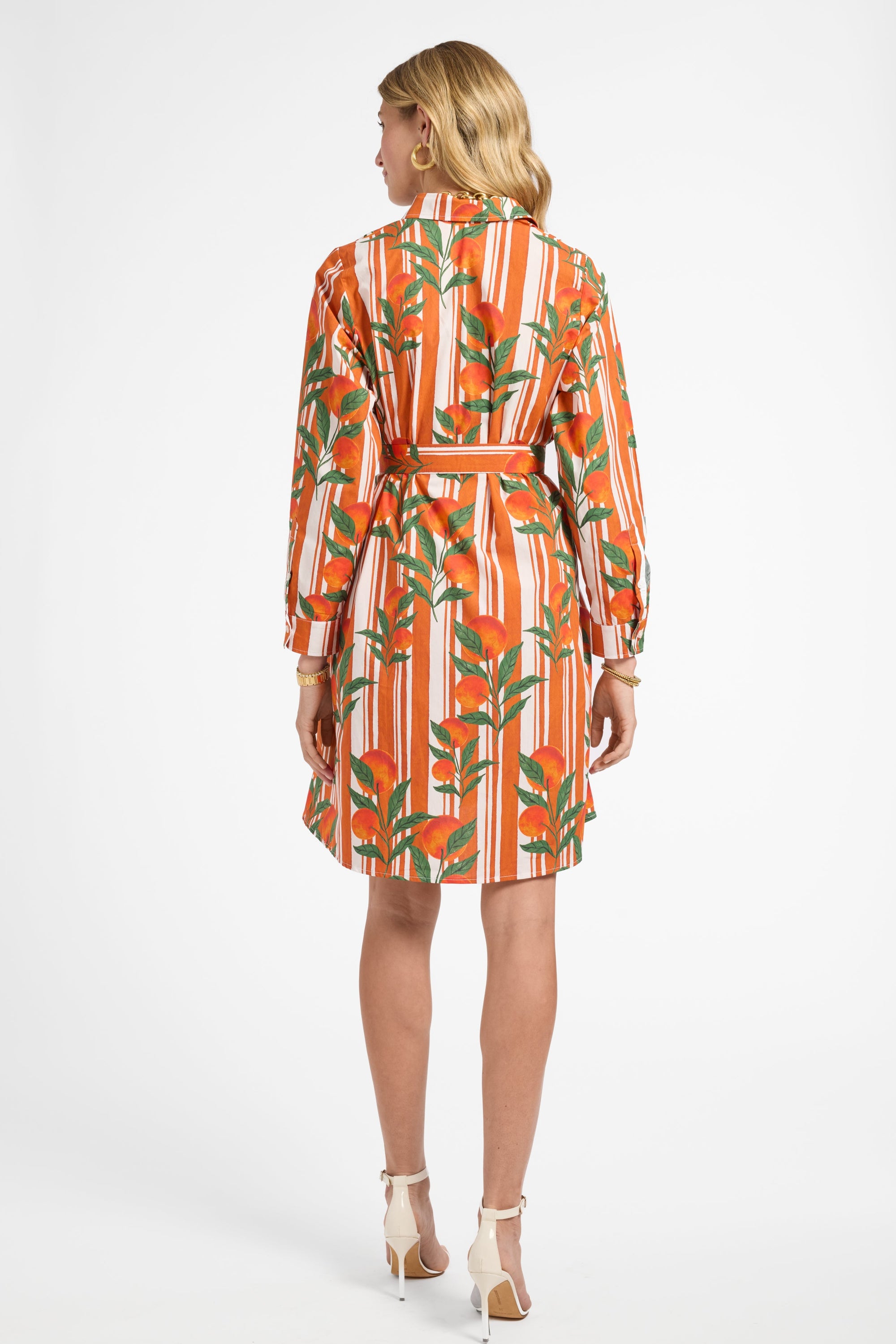 Woman wearing an orange and green patterned dress on a white background