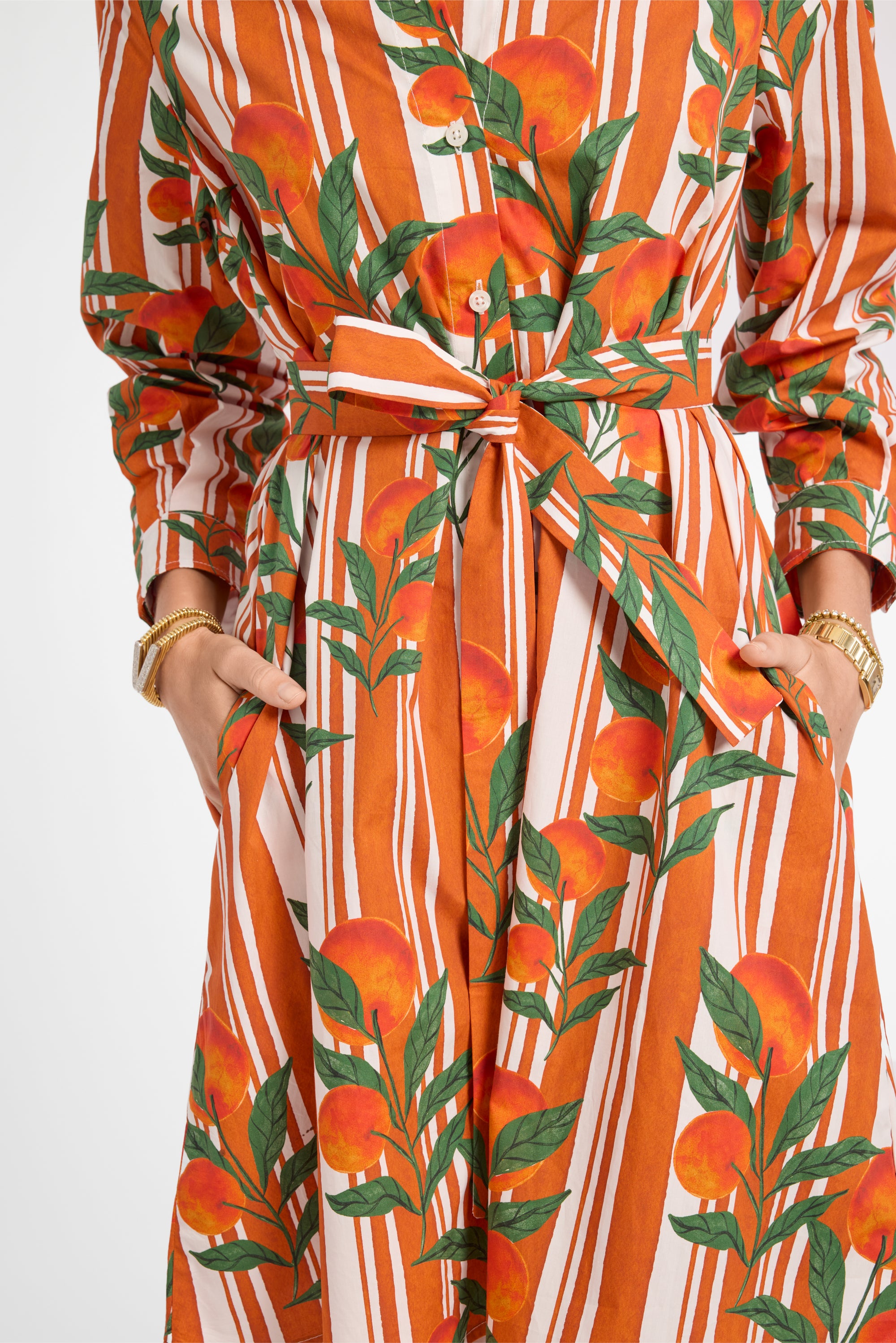 Orange and white striped dress with fruit pattern on a plain background
