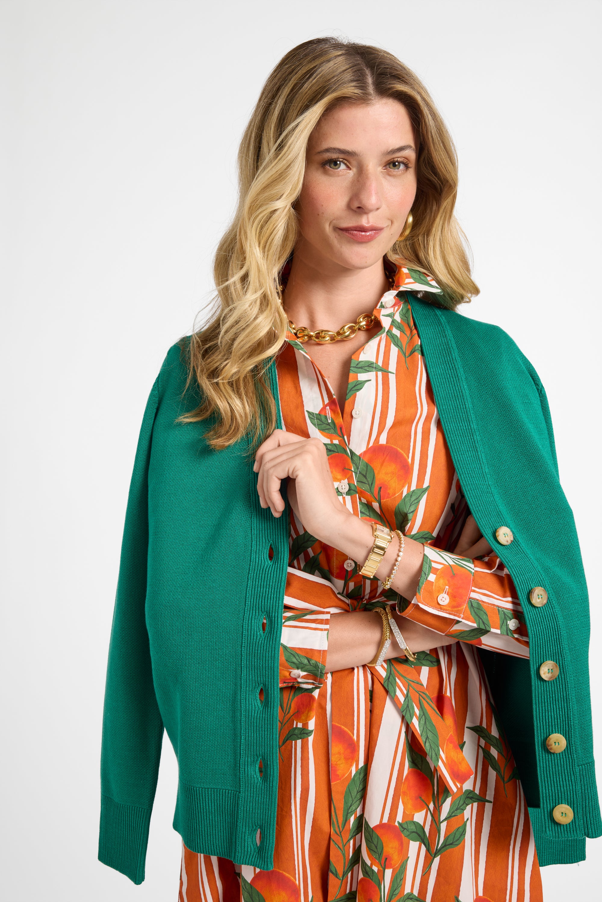 Woman modeling an orange striped dress with a fruit pattern wearing a green cardigan over it