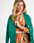Woman modeling an orange striped dress with a fruit pattern wearing a green cardigan over it