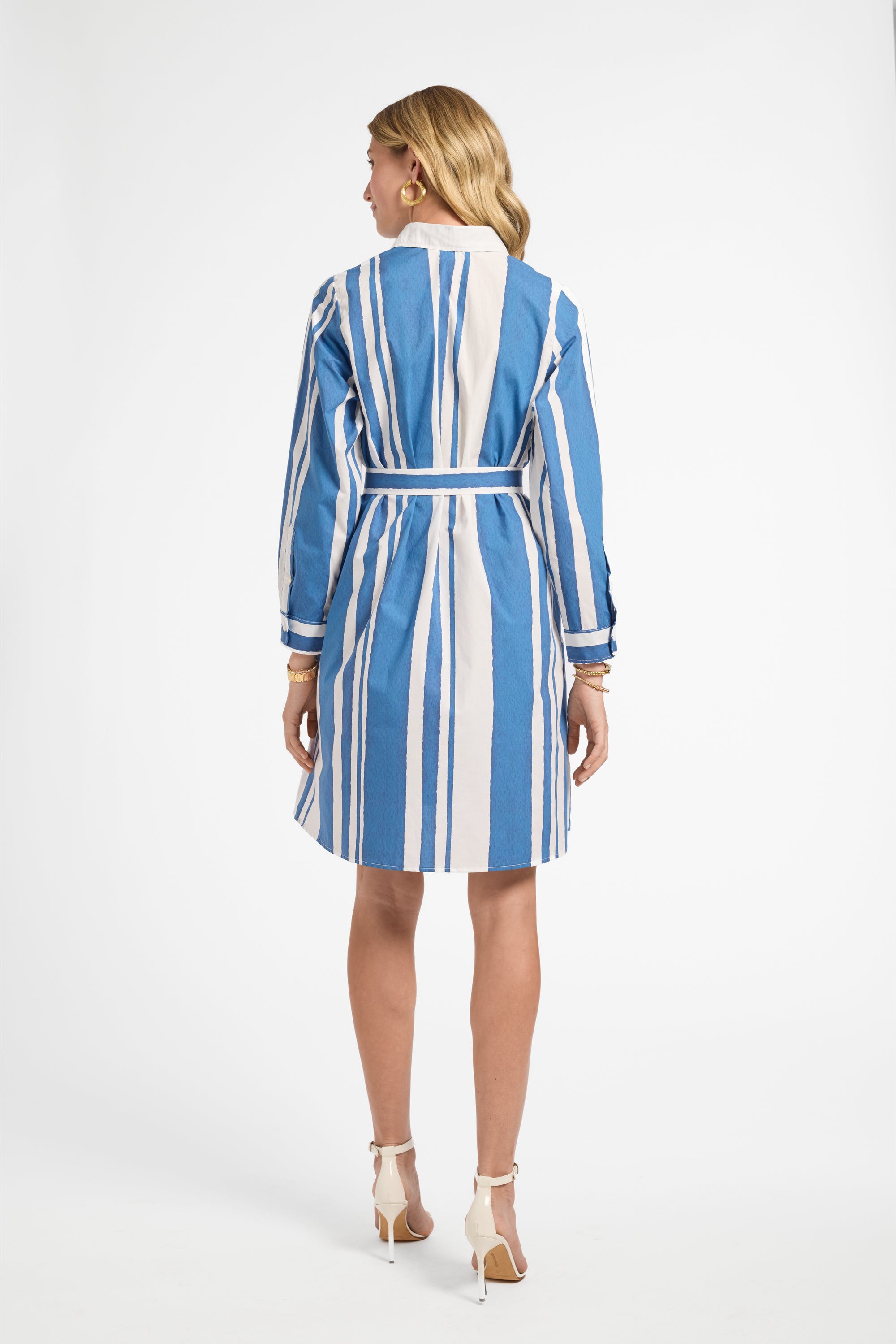 Woman wearing a blue and white striped dress with white heels on a white background