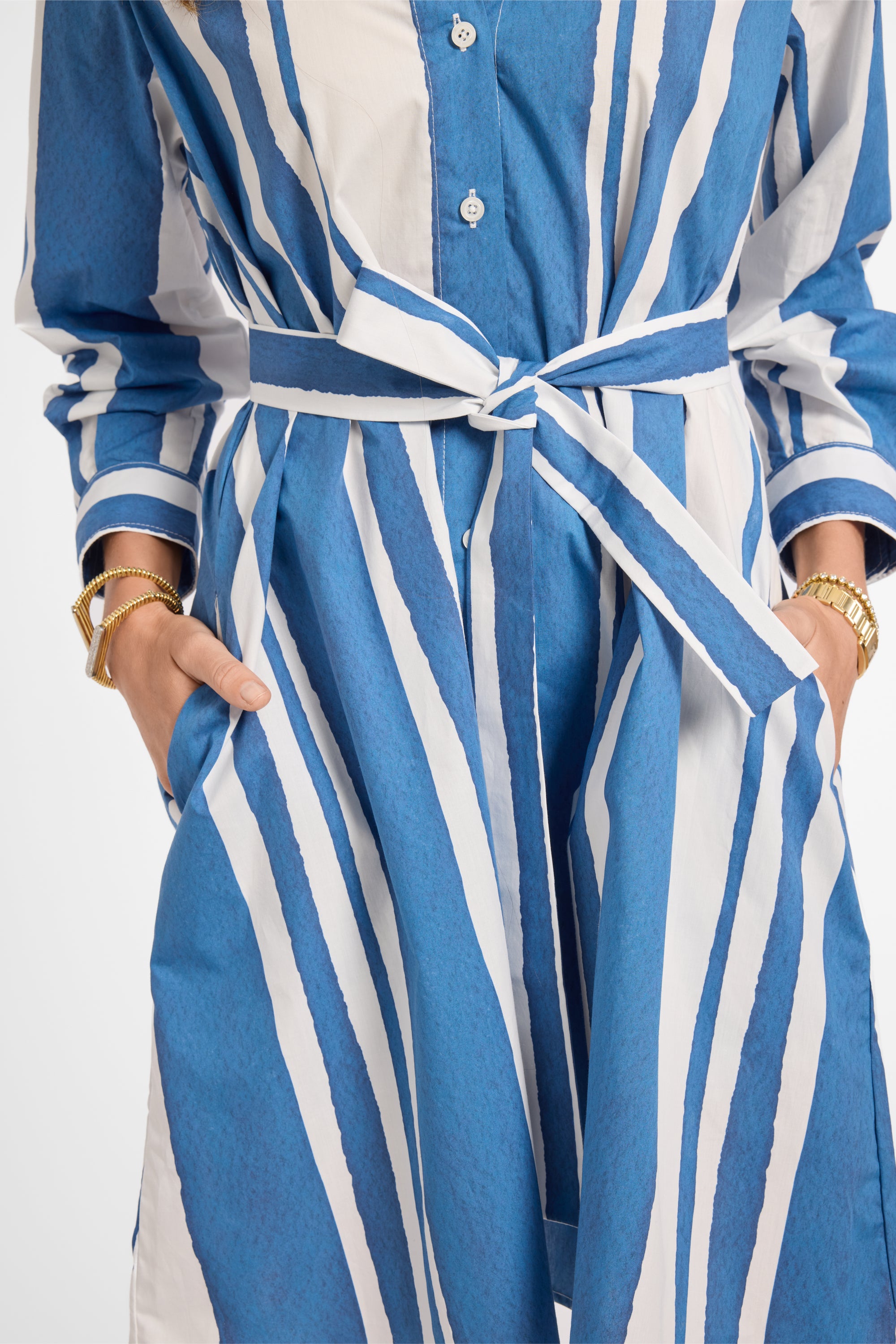 Blue and white striped dress with a tie around the waist on a plain background