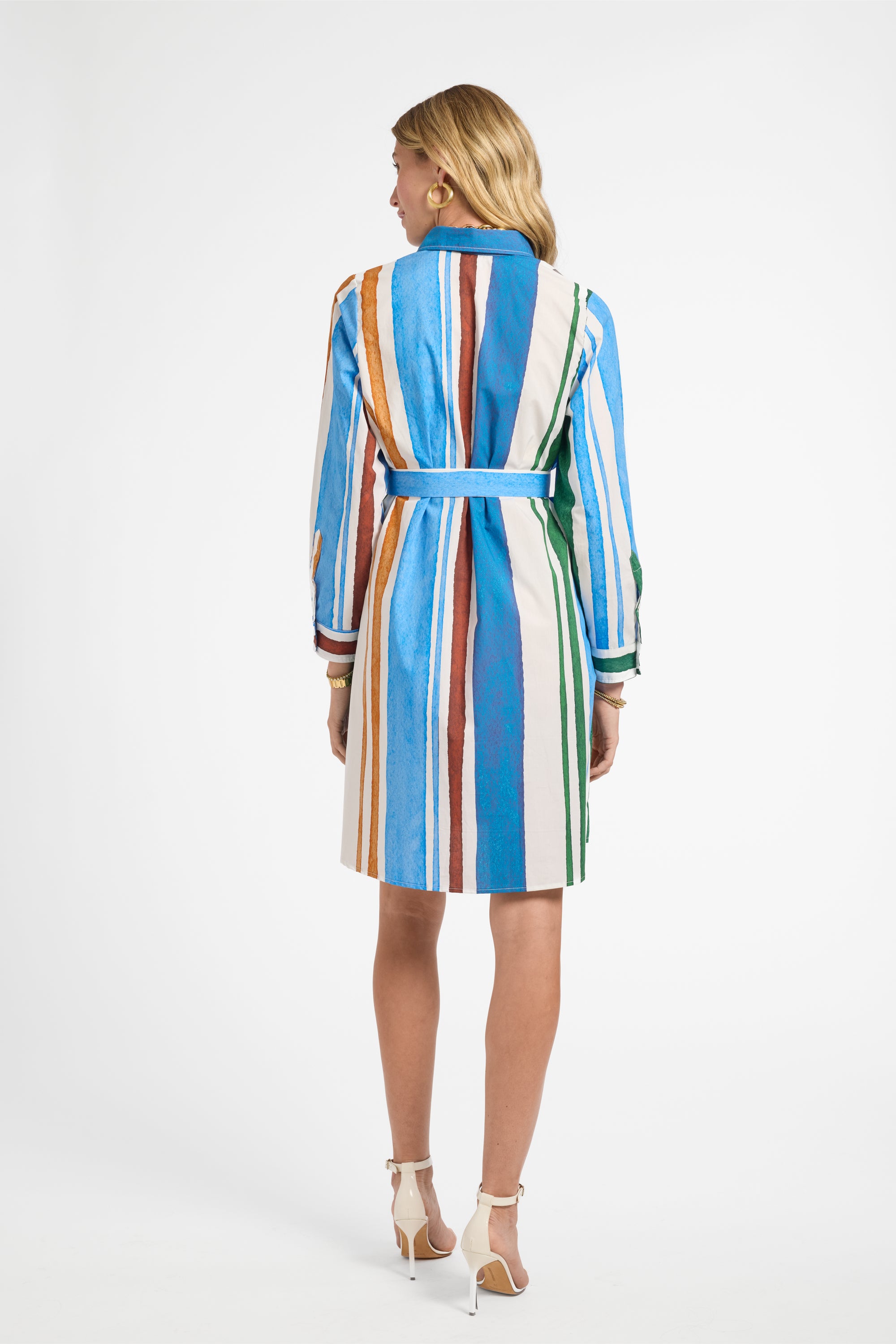 Woman wearing a colorful, mid-length, striped dress on a white background