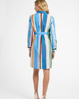 Woman wearing a colorful, mid-length, striped dress on a white background