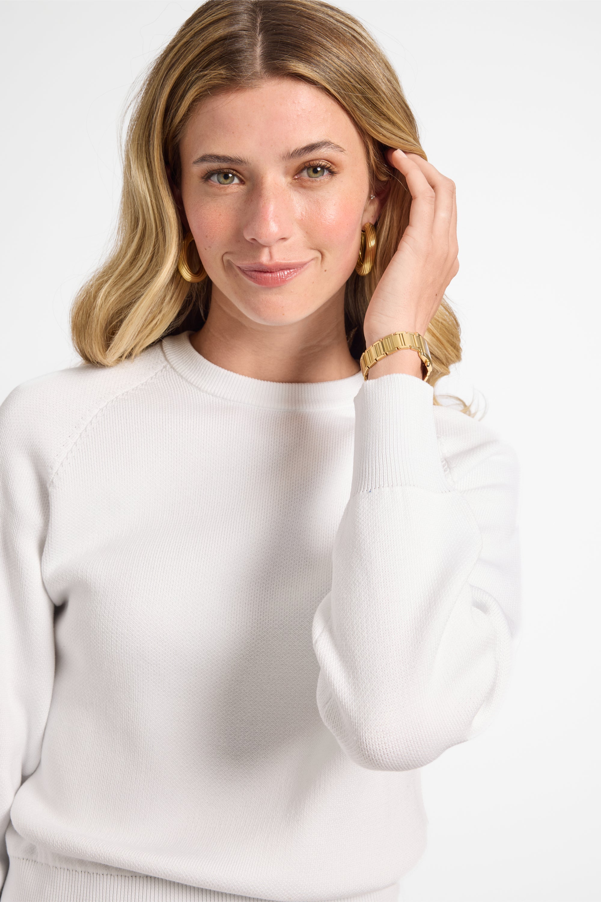 Woman modeling a white sweater on a plain background