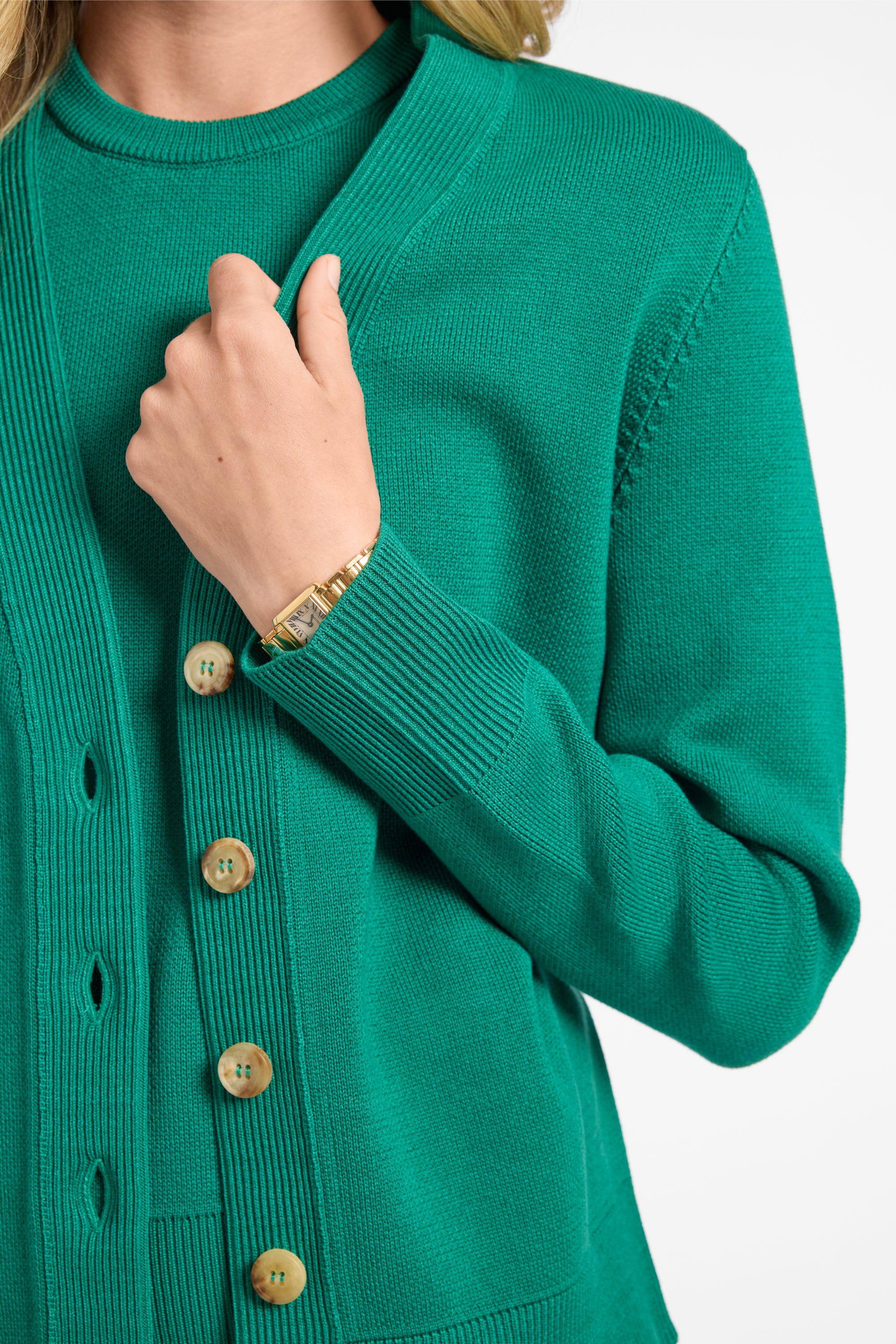 Green cardigan with buttons worn by a person on a white background