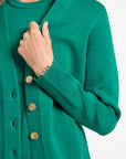 Green cardigan with buttons worn by a person on a white background