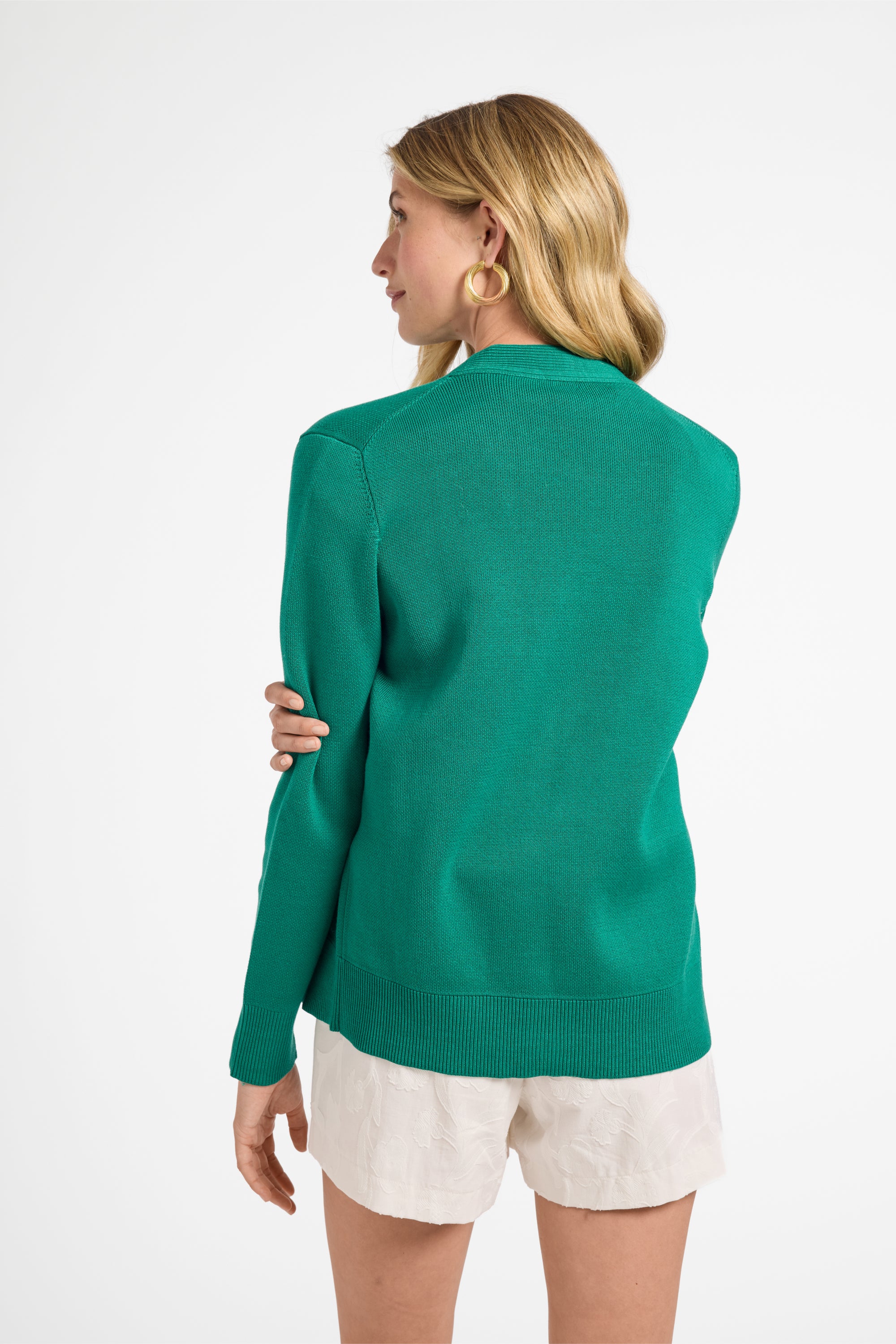 Woman wearing a green sweater and white shorts on a white background