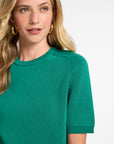 Woman wearing a green short sleeve t-shirt sweater against a white background