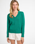 Woman wearing a green sweater and white shorts on a white background