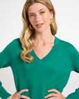 Woman wearing a green v-neck sweater against a white background