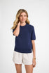 Woman wearing a navy sweater shirt and white shorts on a white background
