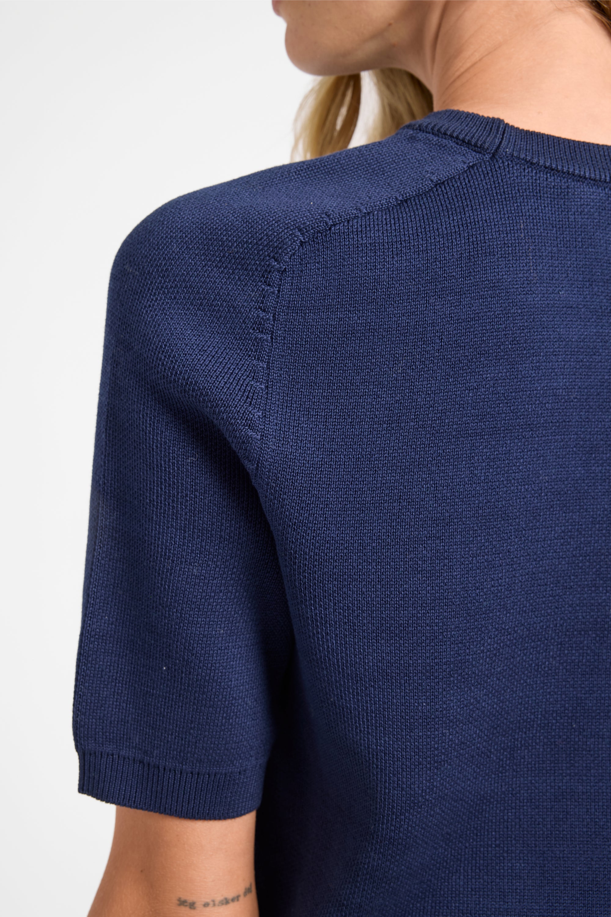 Navy blue short-sleeve top worn by a person on a white background
