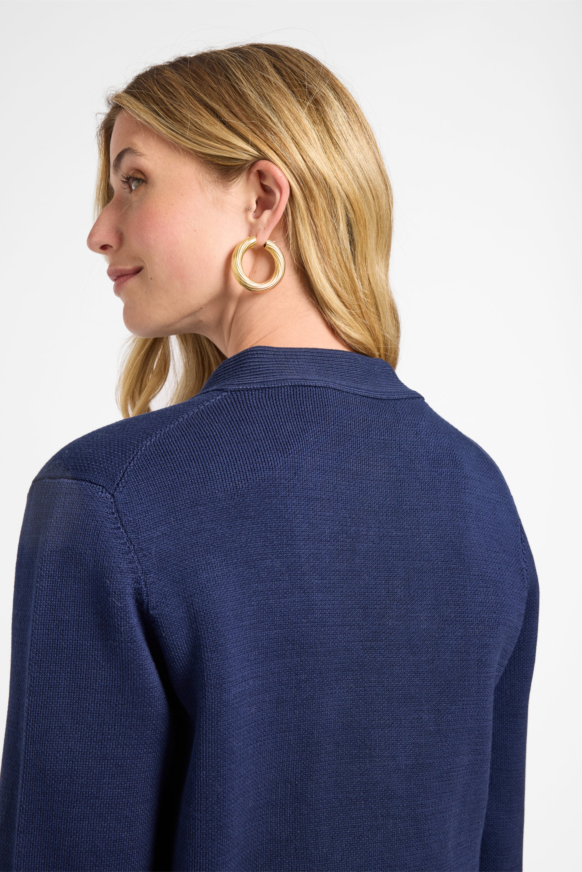 Woman wearing a navy blue sweater with a plain white background