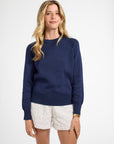 Woman wearing a navy blue crewneck and white shorts on a white background