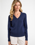 Woman wearing a navy blue sweater and white shorts on a white background