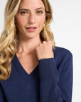 Woman wearing a navy v-neck sweater on a white background