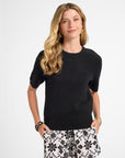 Woman wearing a black top and patterned shorts on a white background