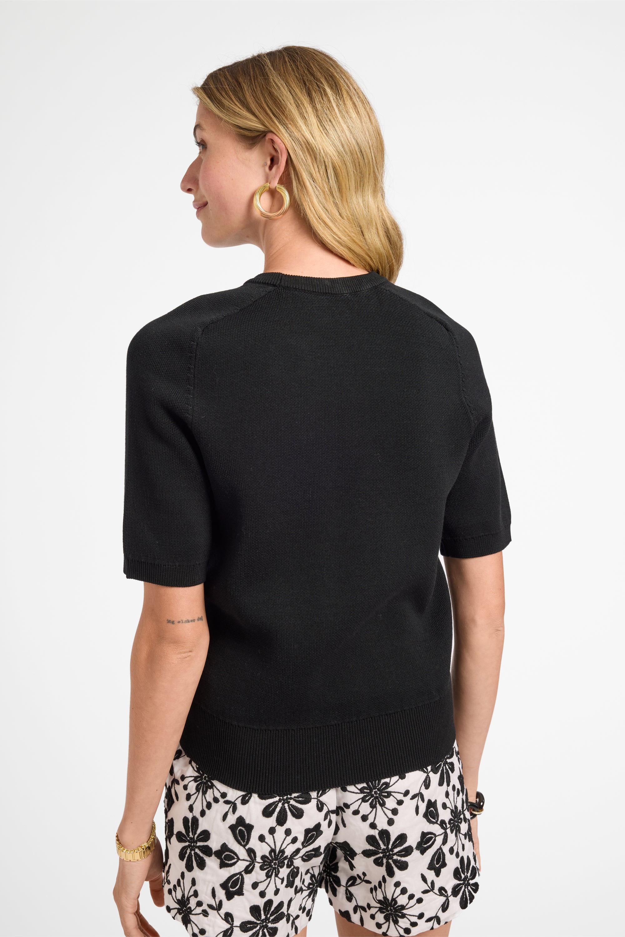 Woman wearing a black top and floral shorts on a white background