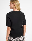 Woman wearing a black top and floral shorts on a white background