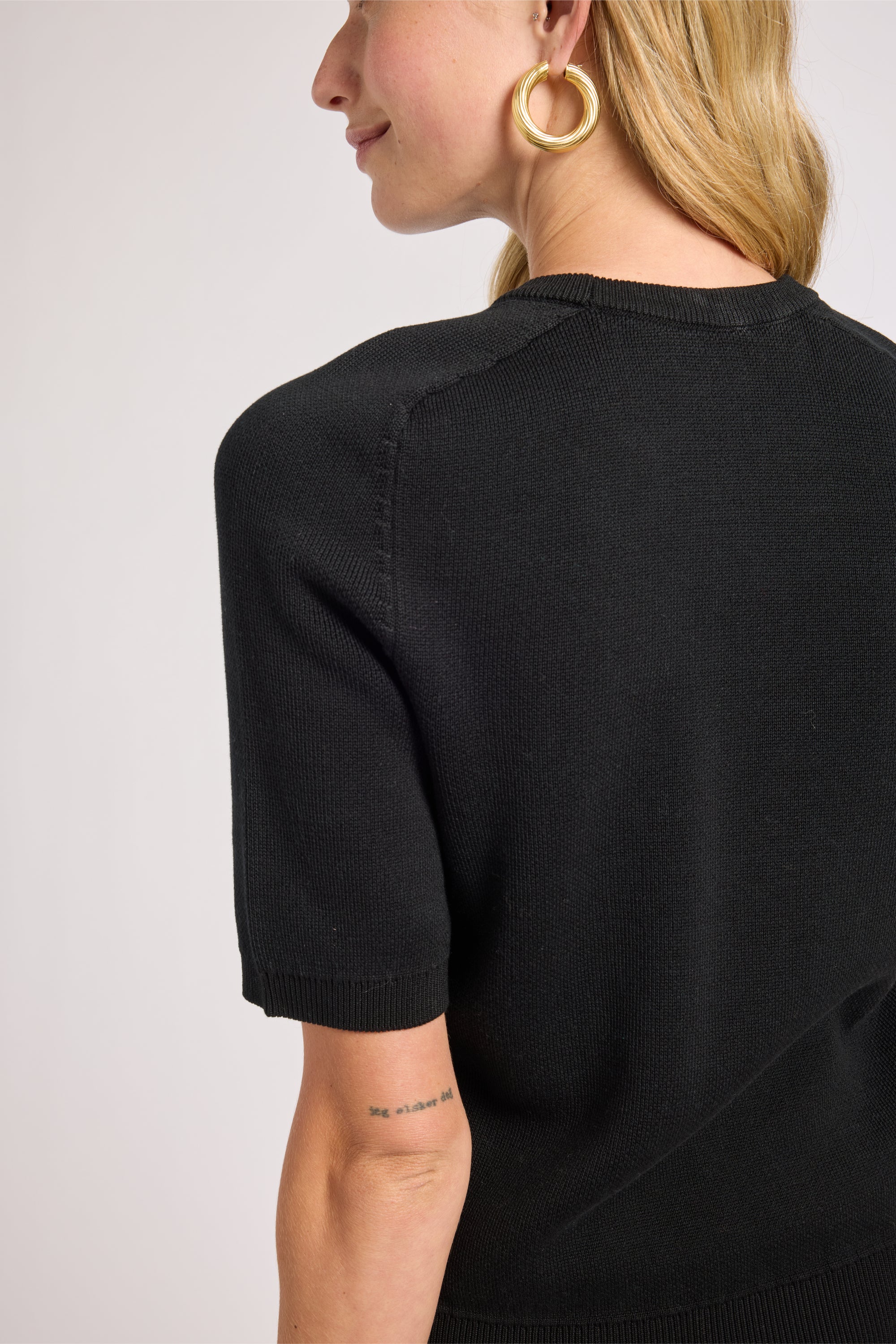 Person wearing a black sweater on a plain background