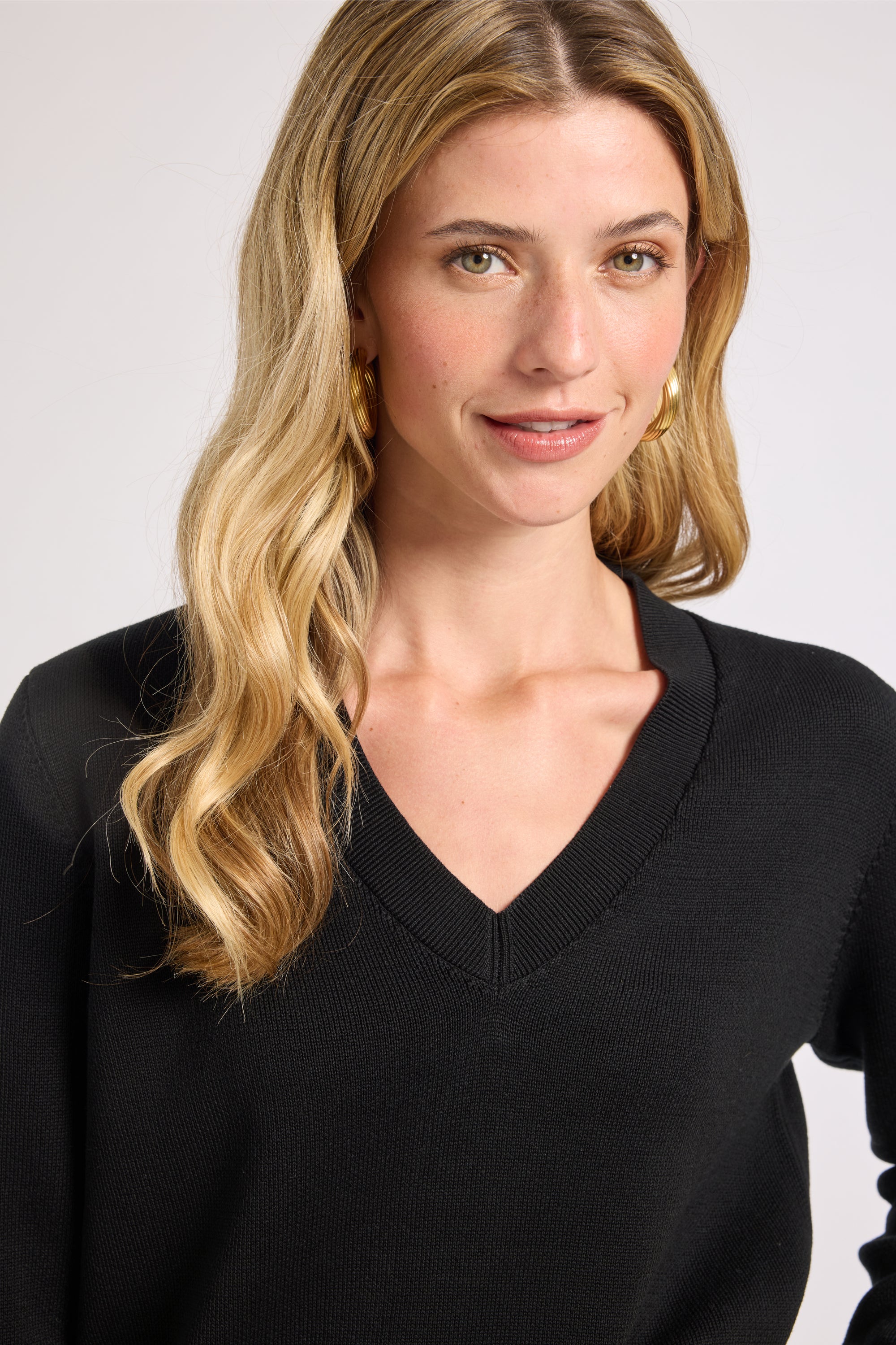 Woman wearing a black sweater against a plain background
