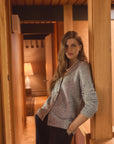 Woman in a home wearing a blue cardigan with a pearl necklace