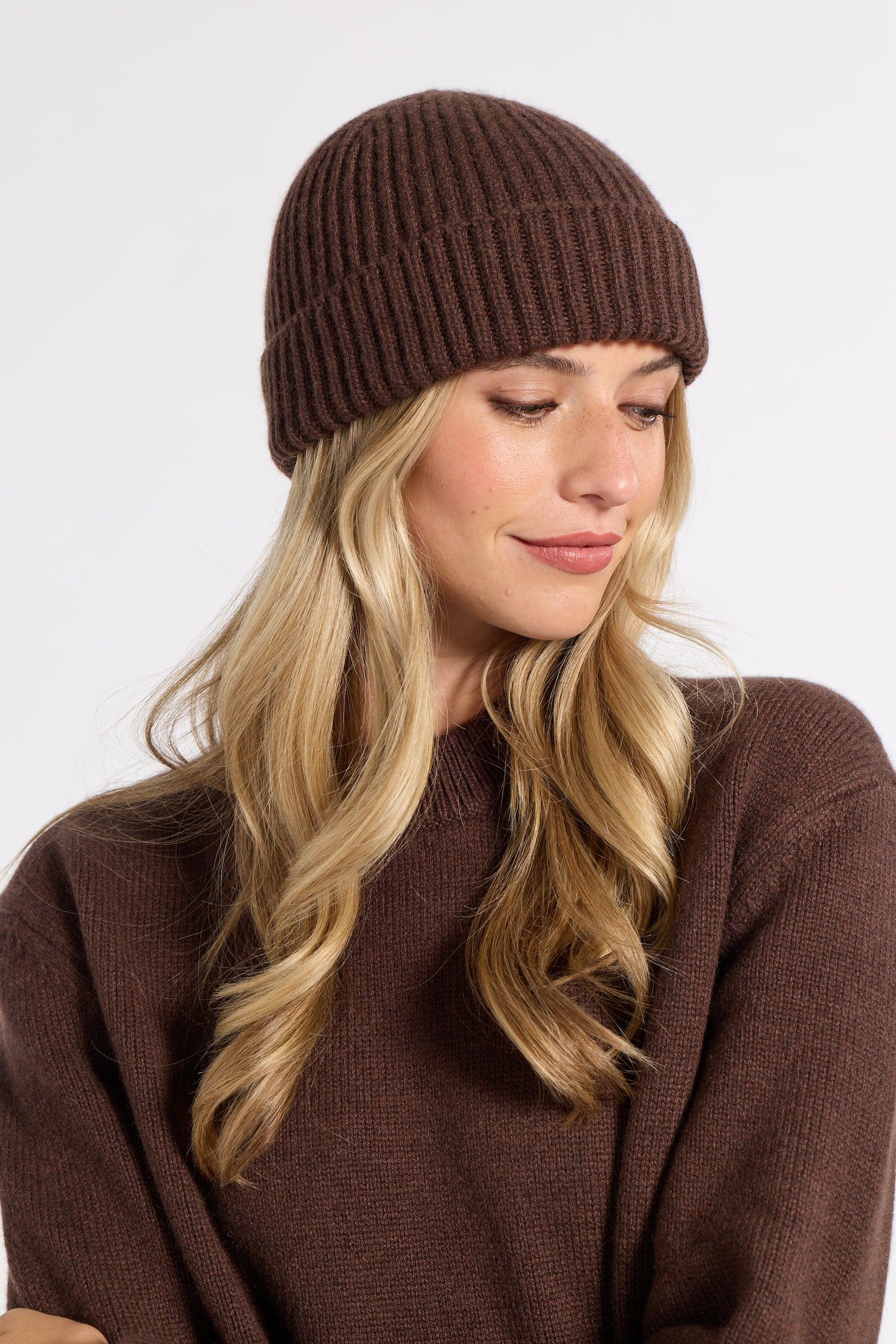 Woman modeling a brown cashmere beanie in a studio