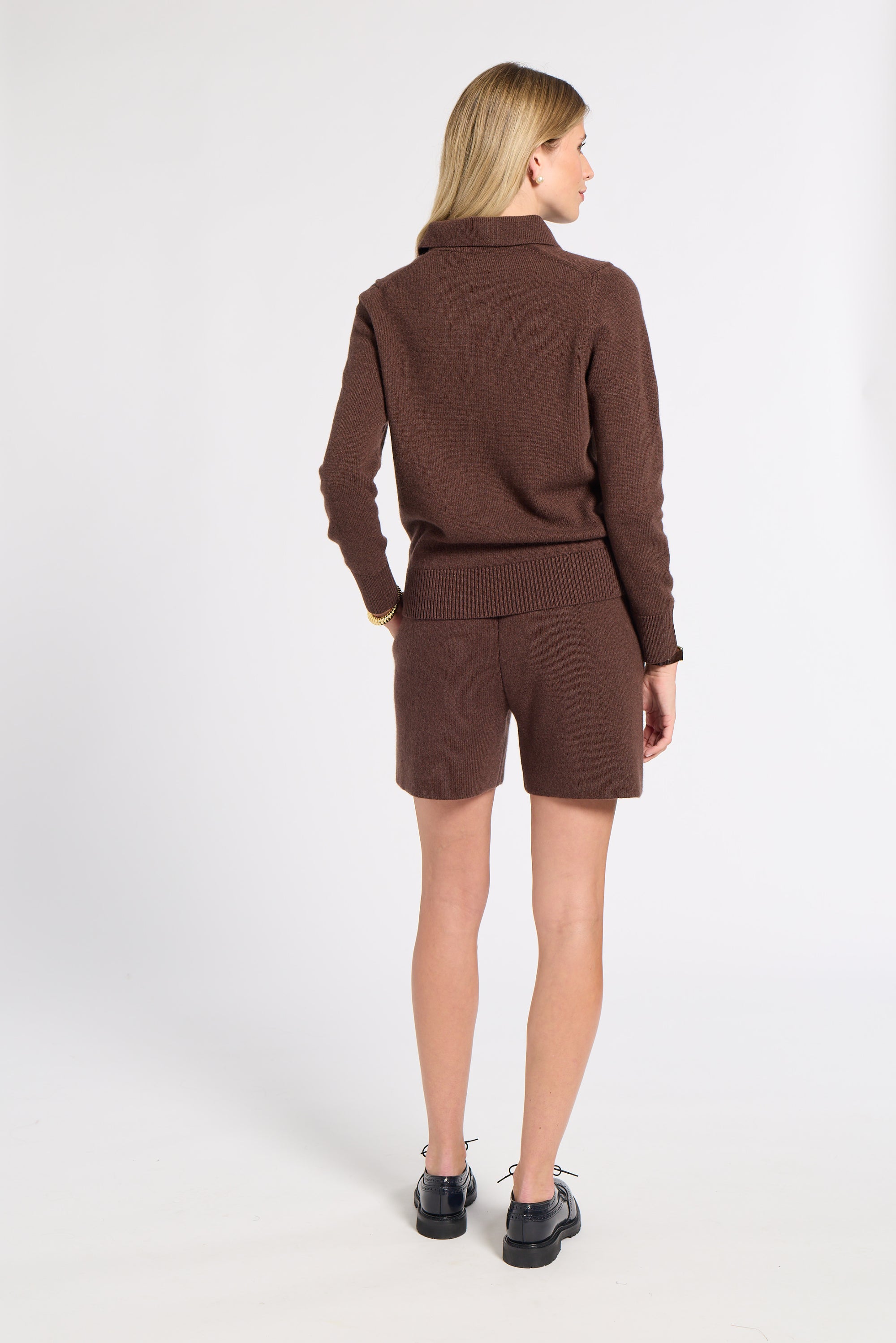 Woman modeling a brown cashmere sweater on a white background