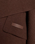 Close-up of a brown ribbed knit garment with a small rectangular leather brand tab reading Barbour.