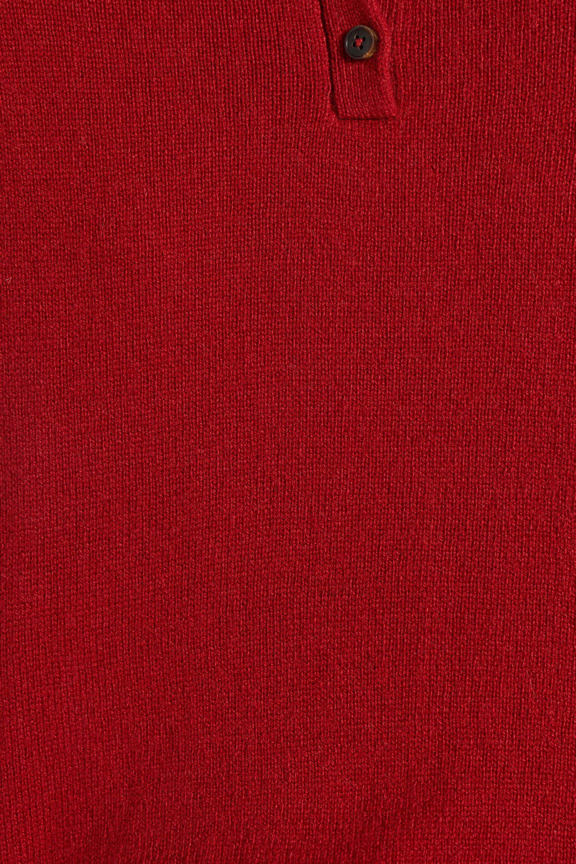 Close-up of a red knit polo shirt showing the textured fabric and a partial buttoned collar.