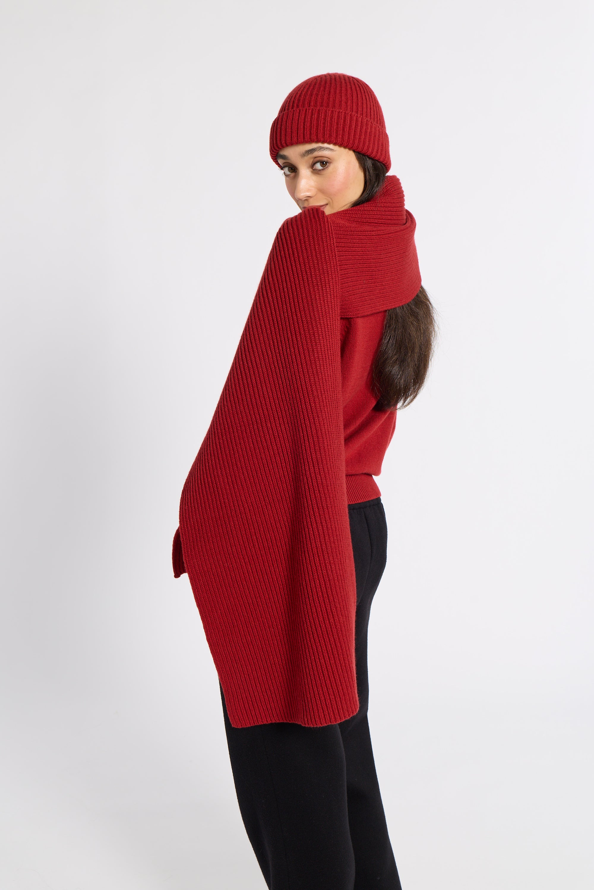 Woman modeling a red cashmere scarf and beanie in a studio