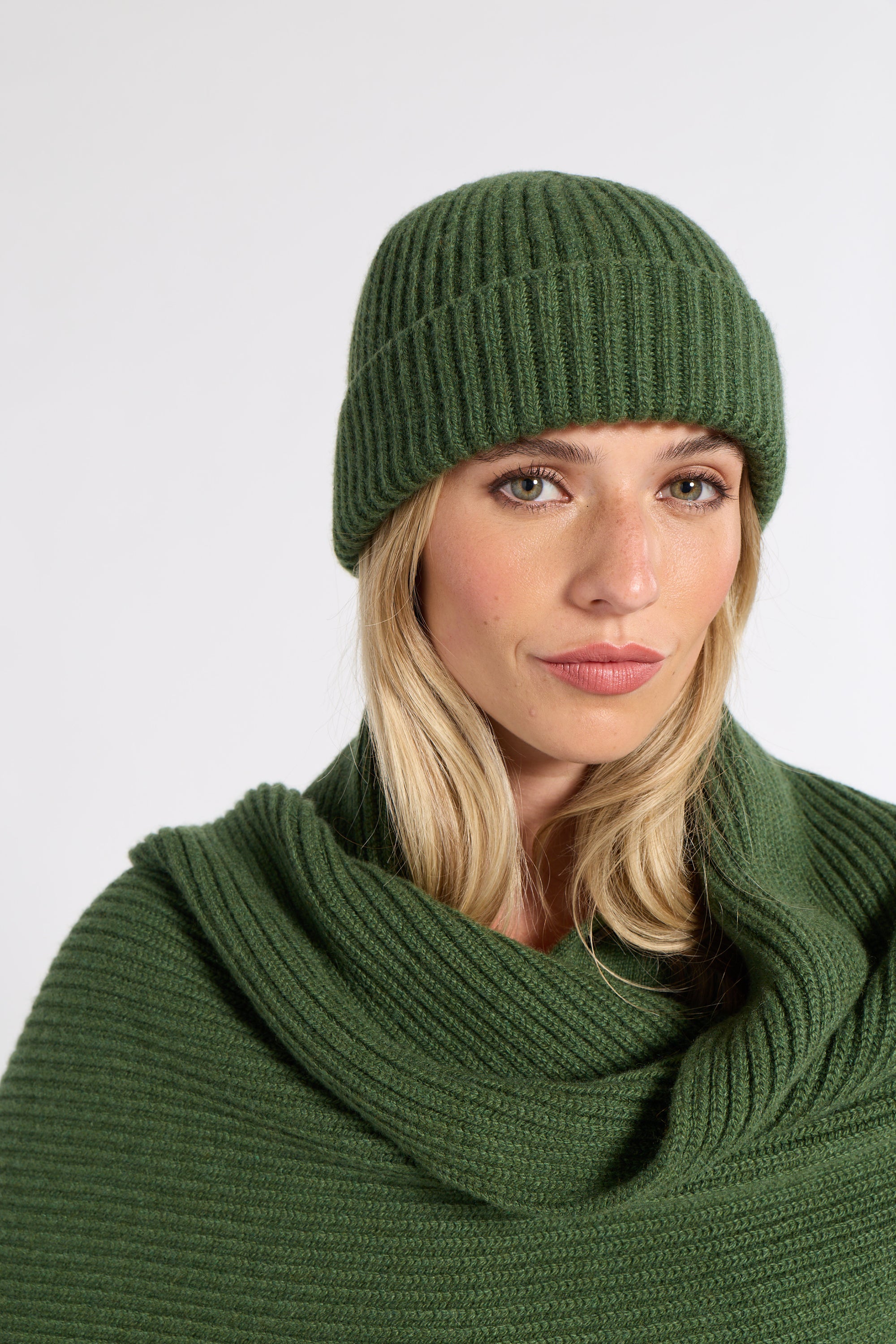 Woman modeling a green cashmere beanie in a studio