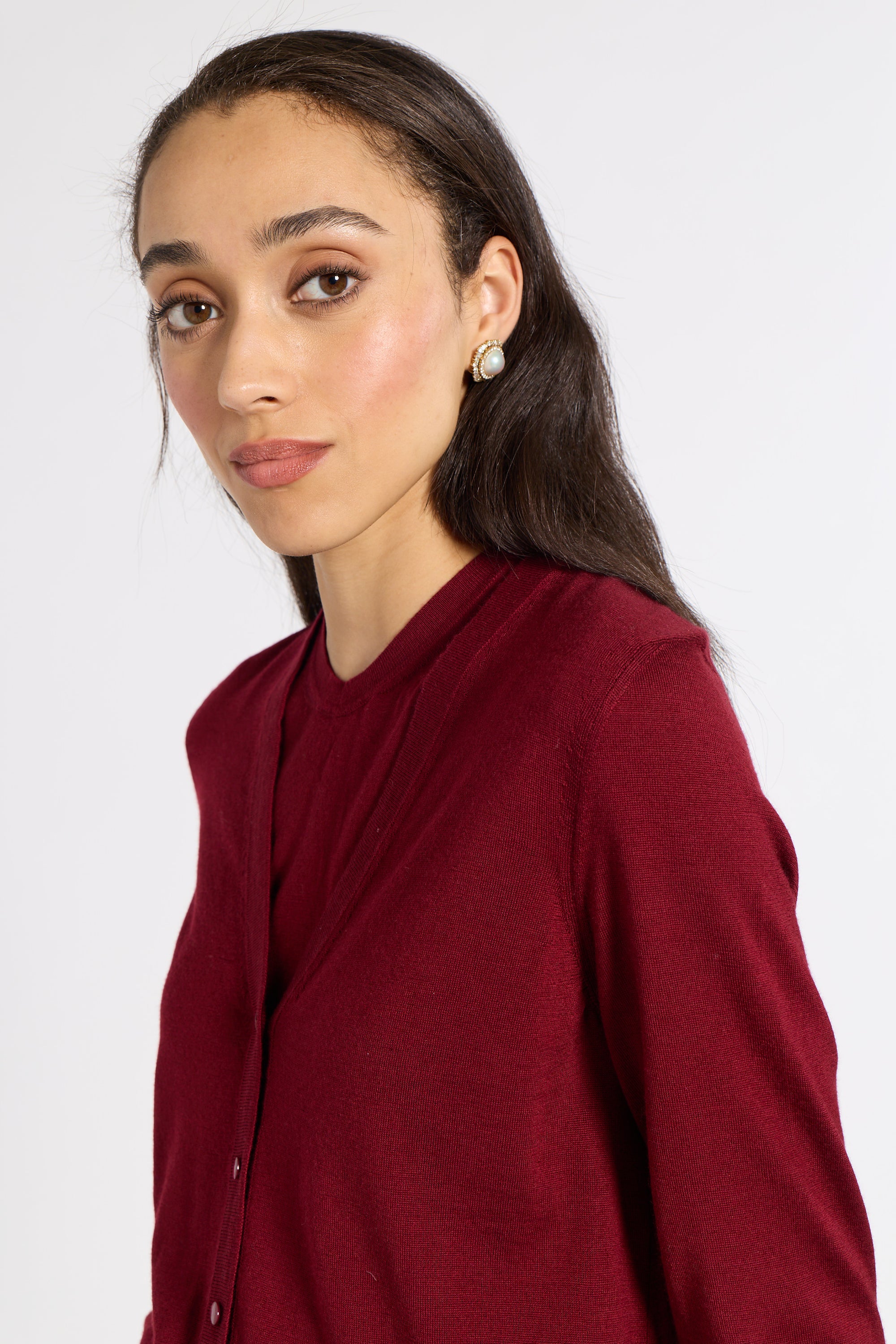 Close up of a woman modeling a red cardigan on a white backdrop
