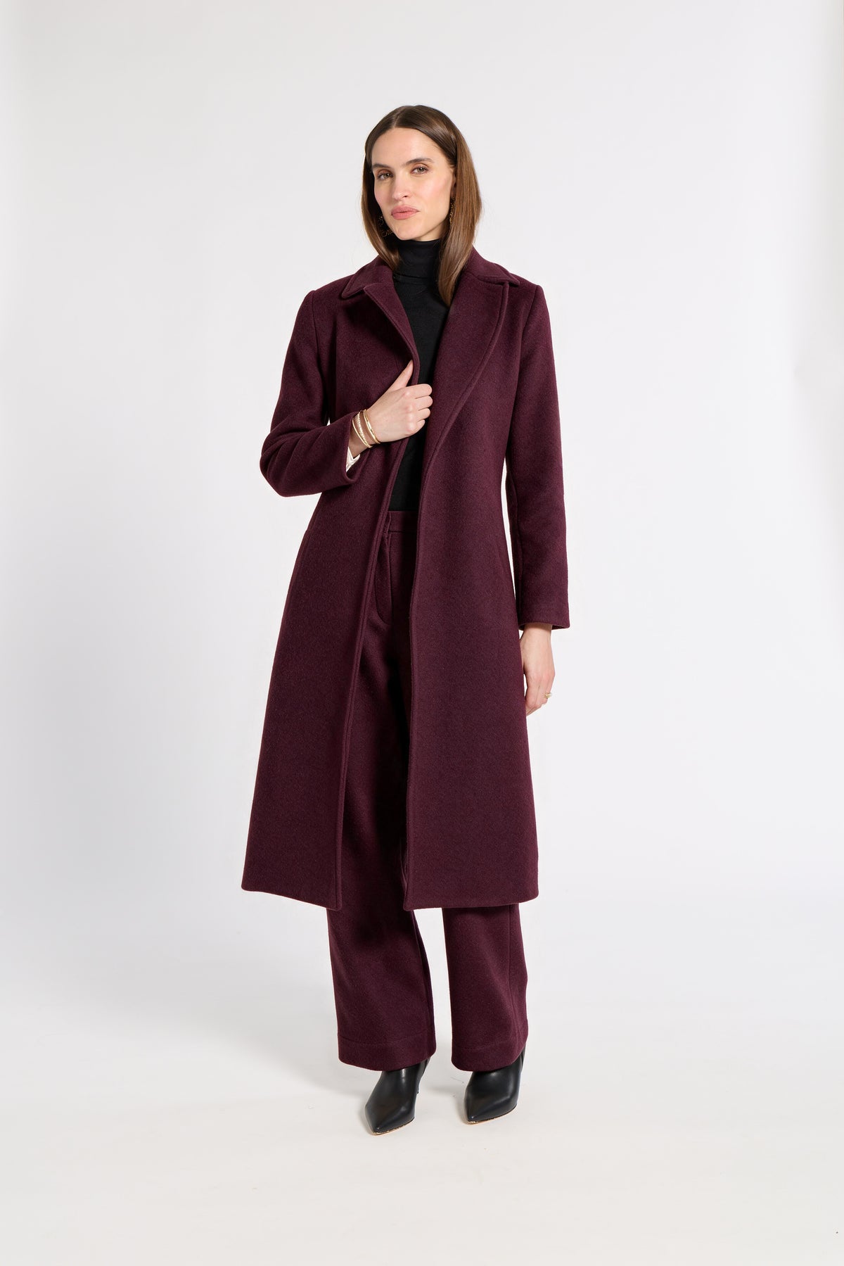 Woman wearing a burgundy cashmere coat in a studio